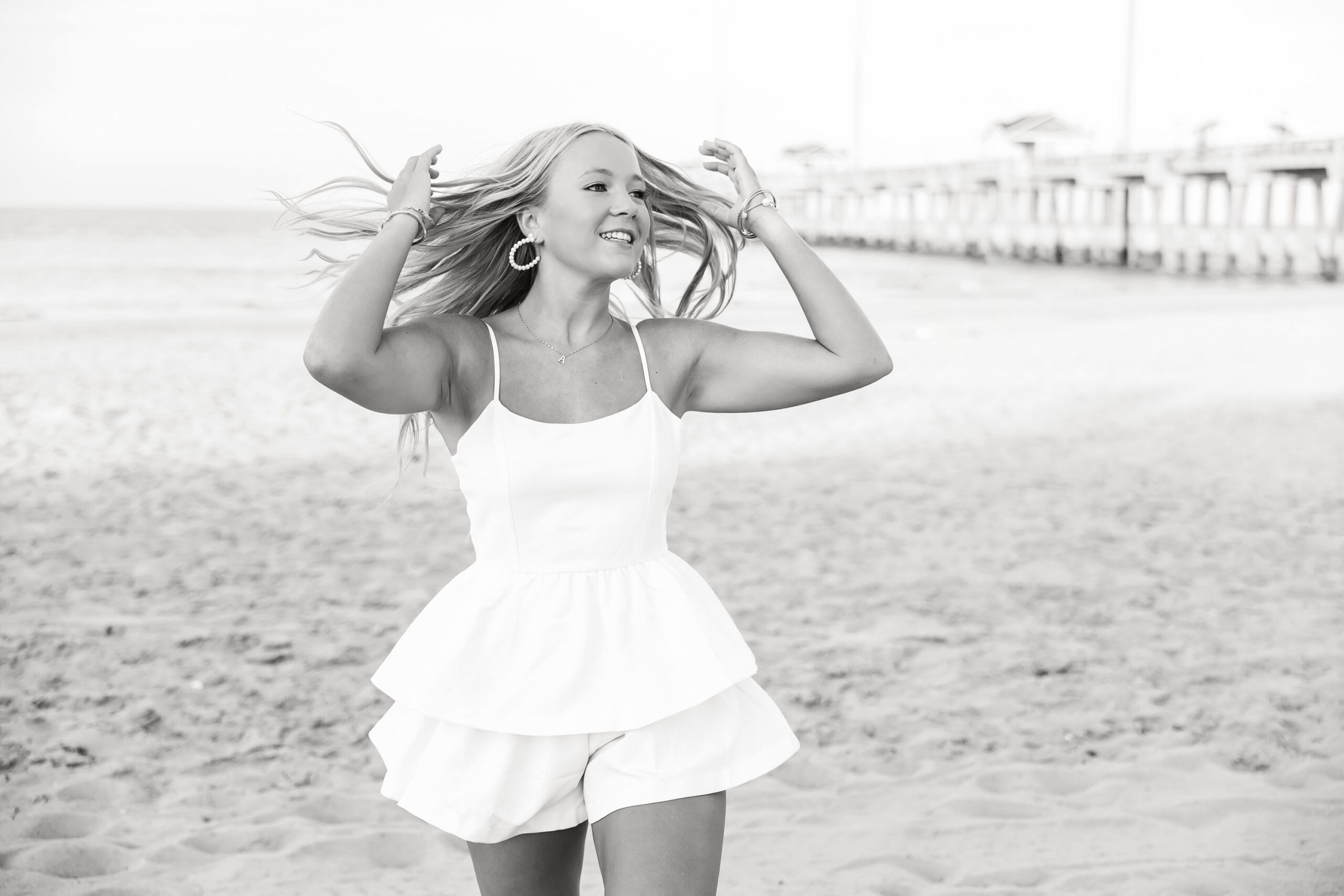 Annabelle walking along Nags Head Beach near Jennette’s Pier in a colorful maxi dress, golden sunshine glowing behind her.