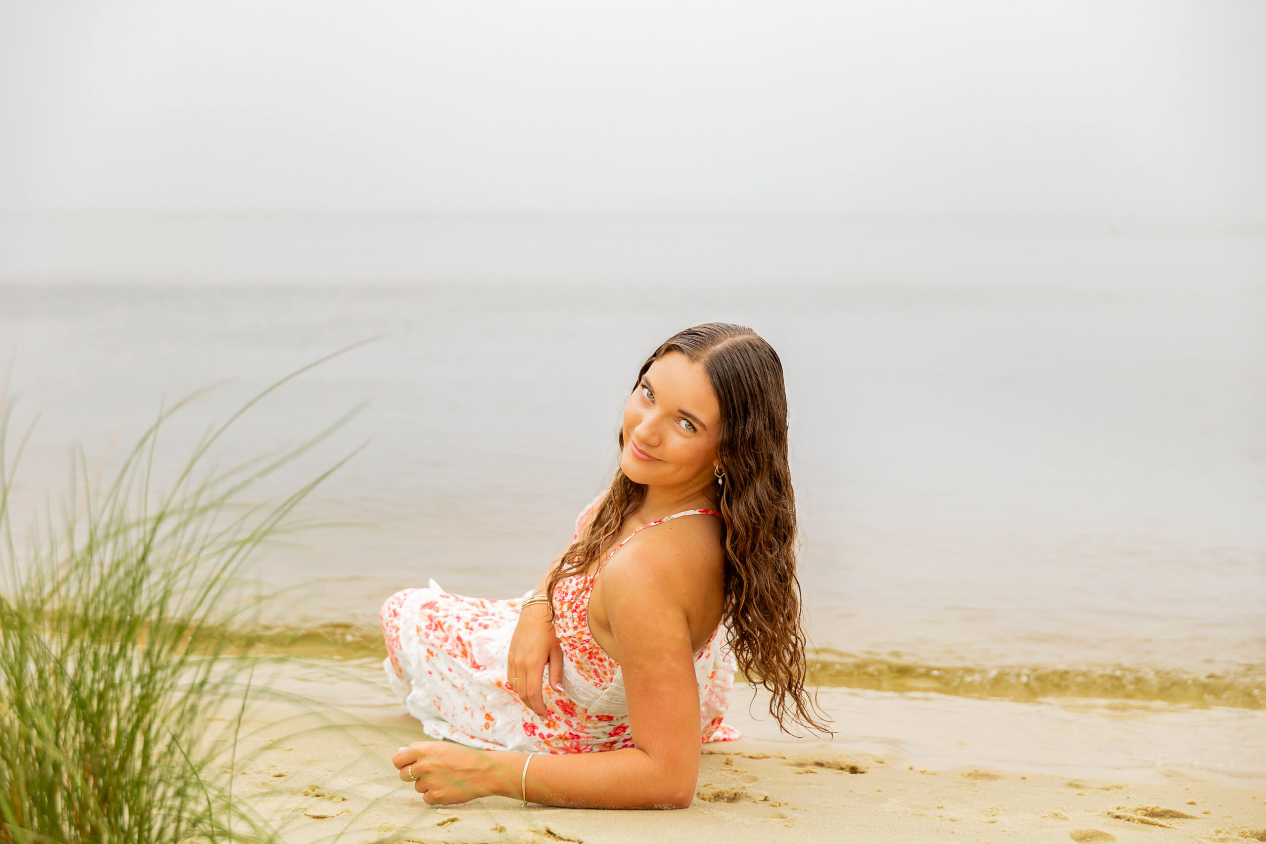 Lilyanne standing in the water at Goose Creek State Park during her senior portrait session, wearing a floral dress and embracing the misty weather.