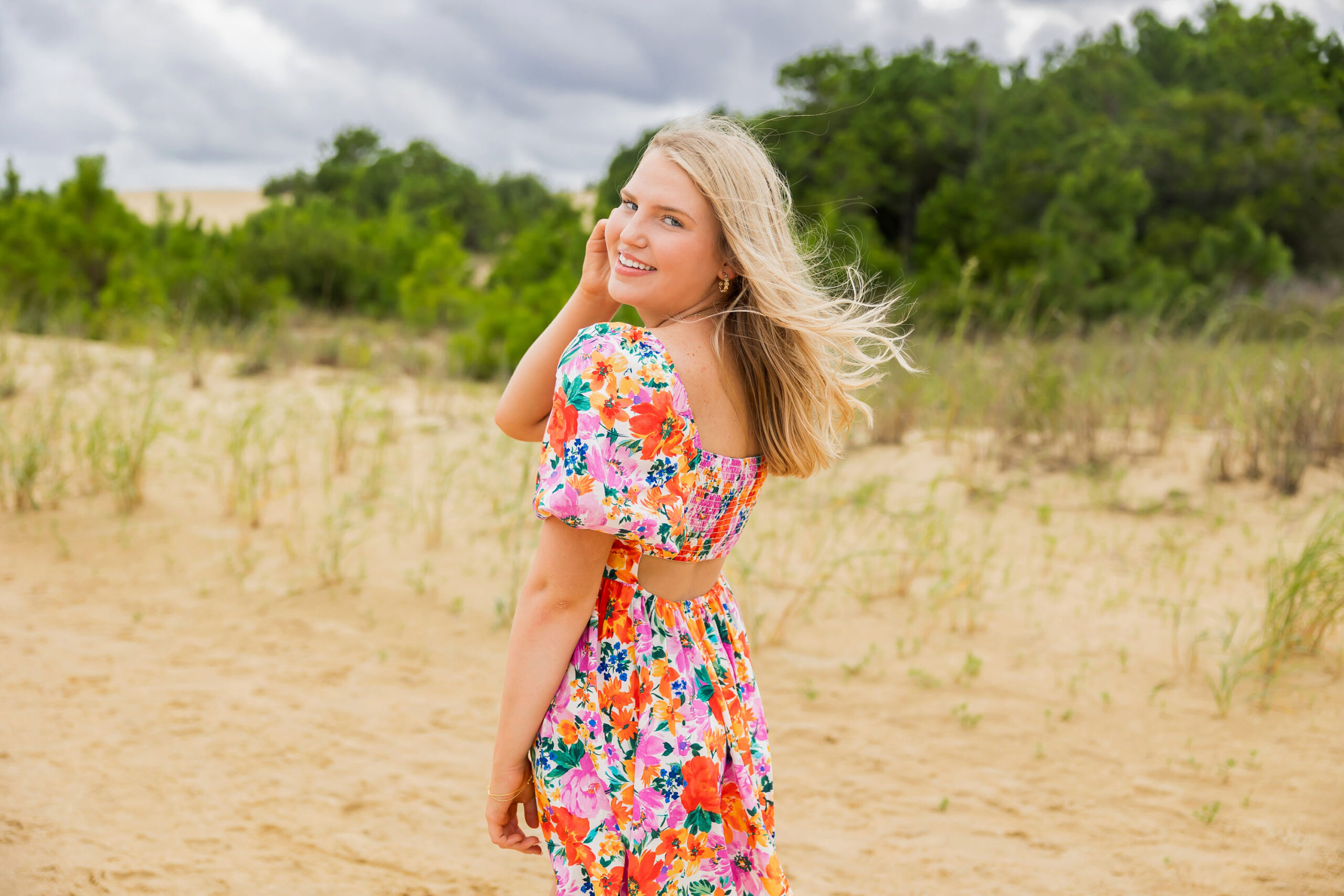 Class of 2026 high school senior walking through Jockey’s Ridge dunes during Outer Banks senior photo session.
