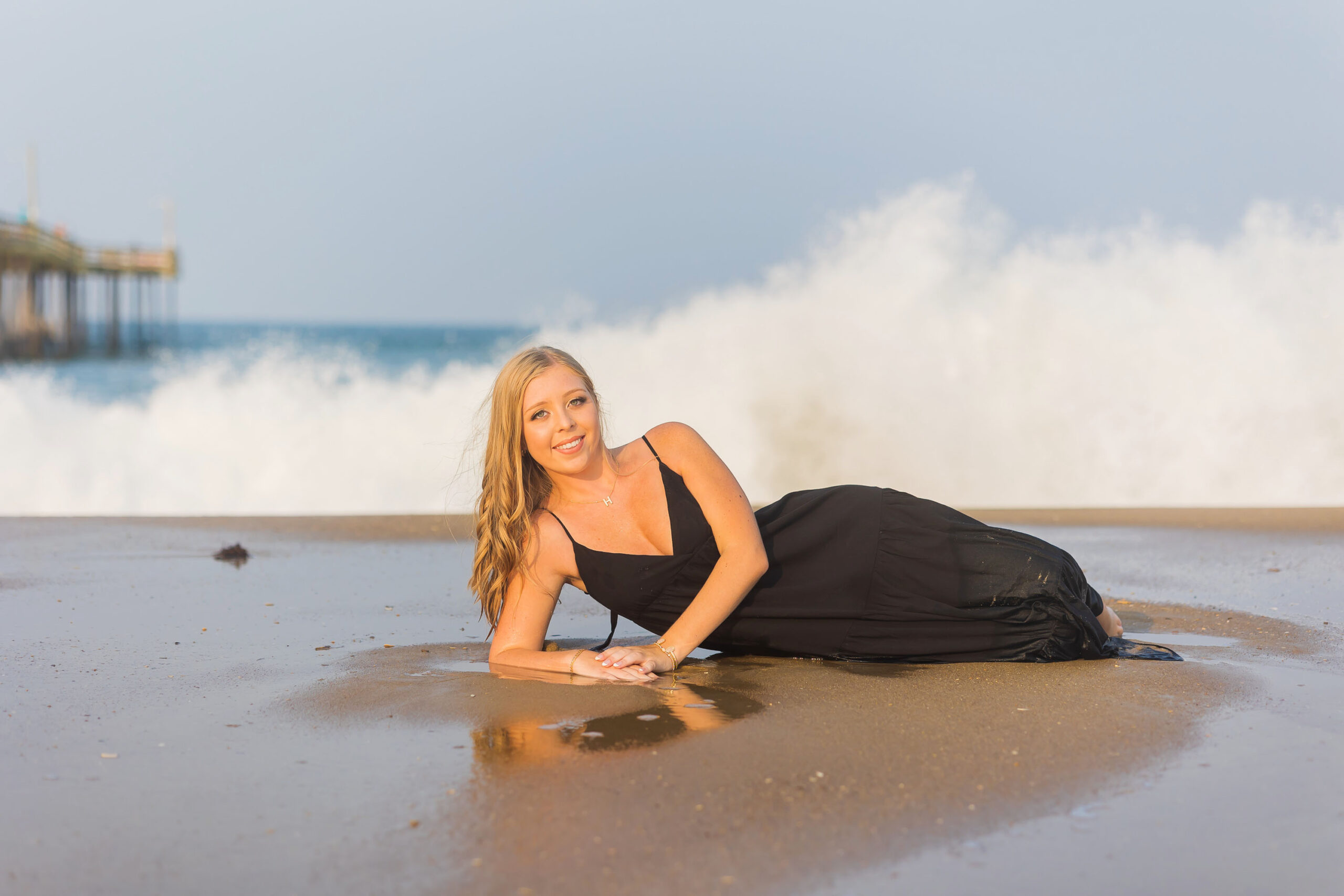 High school senior girl standing beside Nags Head Fishing Pier during Outer Banks senior photo session.