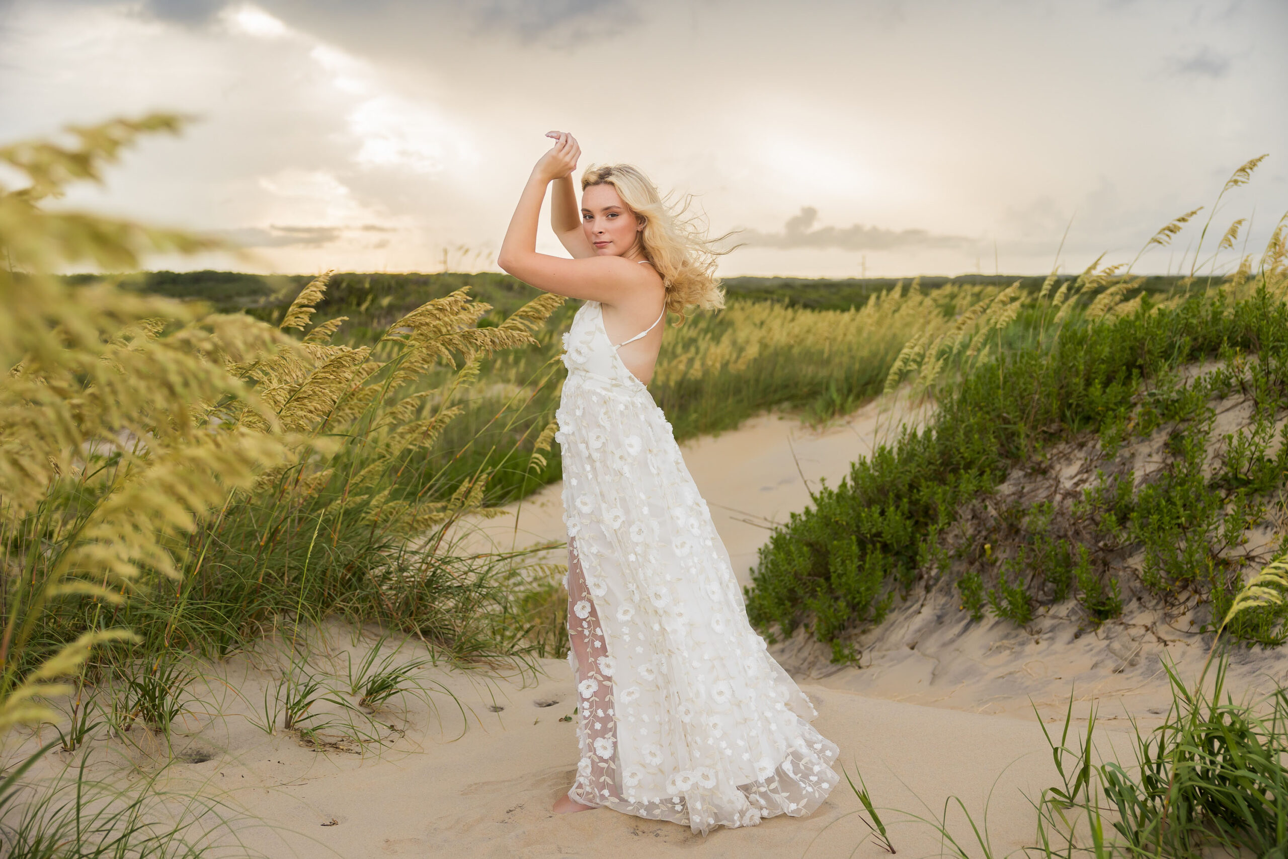 Senior walking across the sand dunes at Coquina Beach, North Carolina during senior photo shoot.
