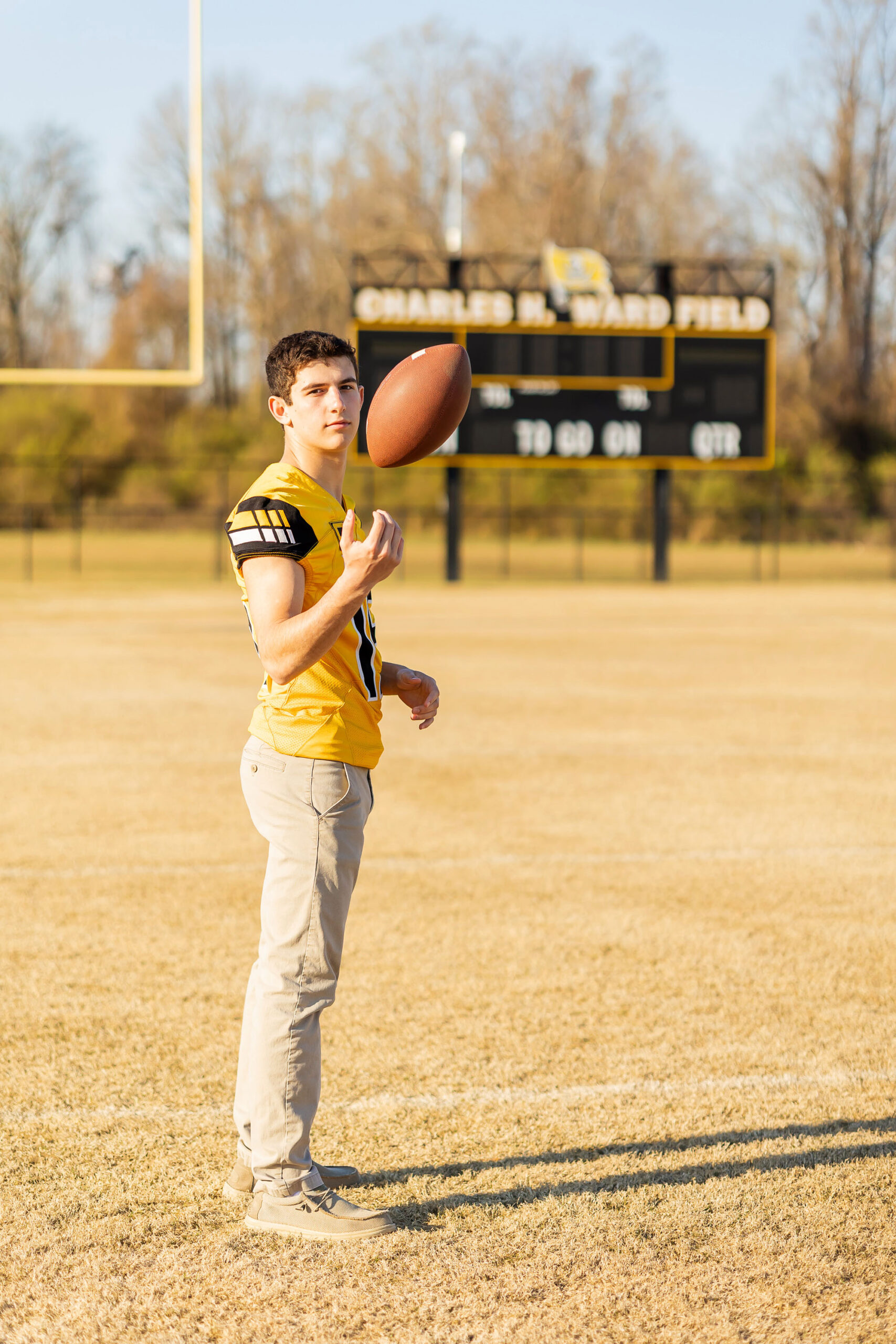 senior guy with football gear during fall senior photo session in North Carolina.
