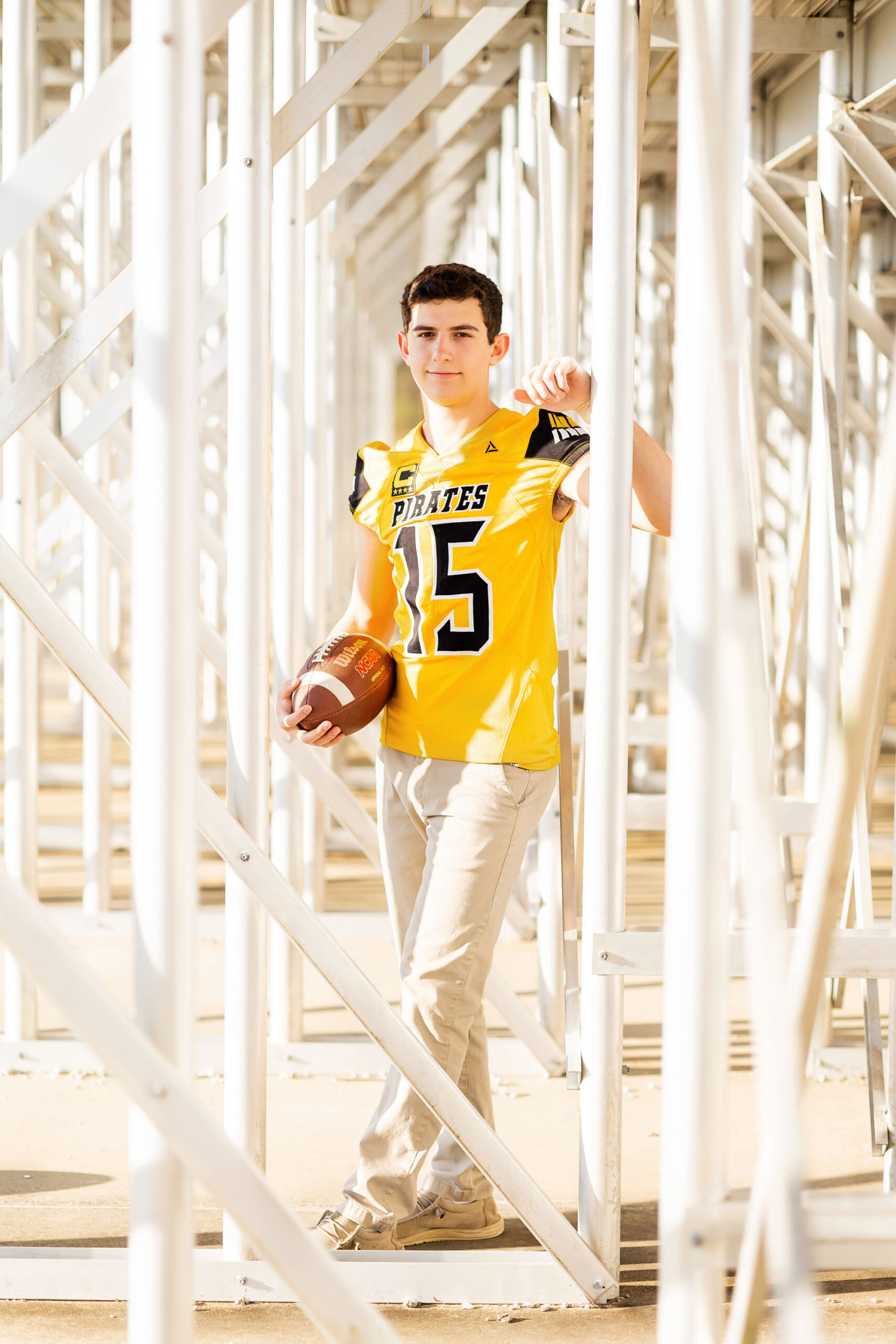 senior guy with football gear during fall senior photo session in North Carolina.