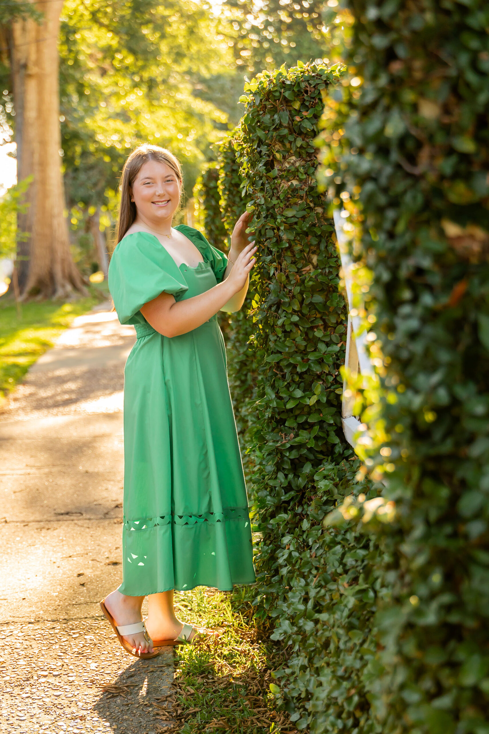 Emily’s summer senior portrait in Downtown Edenton, wearing a green flowy dress along the tree-lined sidewalk, photographed by Sarah Hilts Photography.